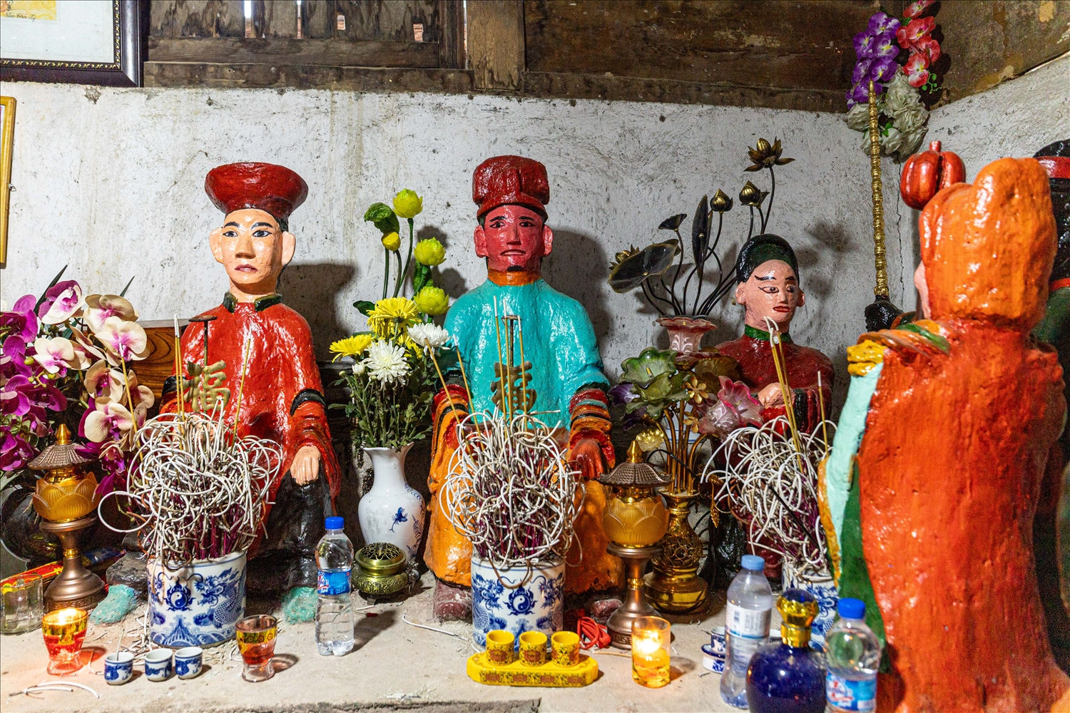 Phía ngoài của ban thờ Lôi thần là tượng thần Thổ Địa và ông Đặng Minh Đông. Trong đó, tượng thần Thổ Địa toạ trên bệ, đầu đội mũ, mắt nhìn xuống, miệng tươi cười, mặc áo màu xanh, cổ áo và ống tay áo được viền màu vàng, xanh, đen, quần màu vàng, tay trái đặt úp trên gối, tay phải cầm đính bạc để ngửa trên gối.