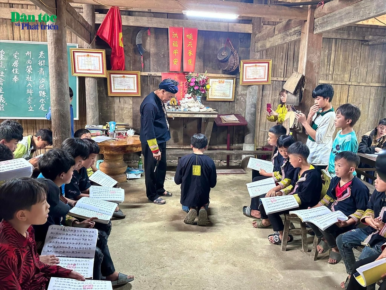 Nghệ nhân Ưu tú Tẩn Vần Siệu đang hướng dẫn các em nhỏ học chữ Nôm Dao, thực hành những nghi thức cúng bái đầu tiên trong đời Nghệ nhân Ưu tú Tẩn Vần Siệu đang hướng dẫn các em nhỏ học chữ Nôm Dao, thực hành những nghi thức cúng bái đầu tiên trong đời