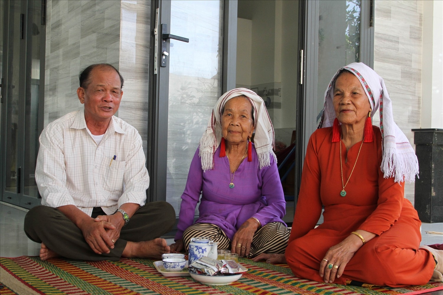 Ông Dương Tấn Kiểm, Bí thư Chi bộ thôn Phú Nhuận thăm hỏi động viên Nghệ nhân Châu Thị Đông truyền dạy chữ Chăm và Ariya cho người dân địa phương. 