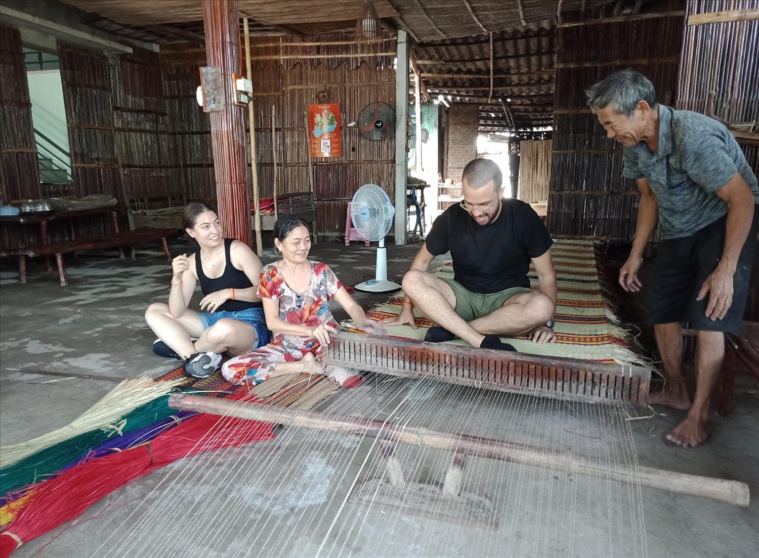 Du khách nước ngoài thích thú trải nghiệm nghề dệt chiếu ở Trà Nhiêu.