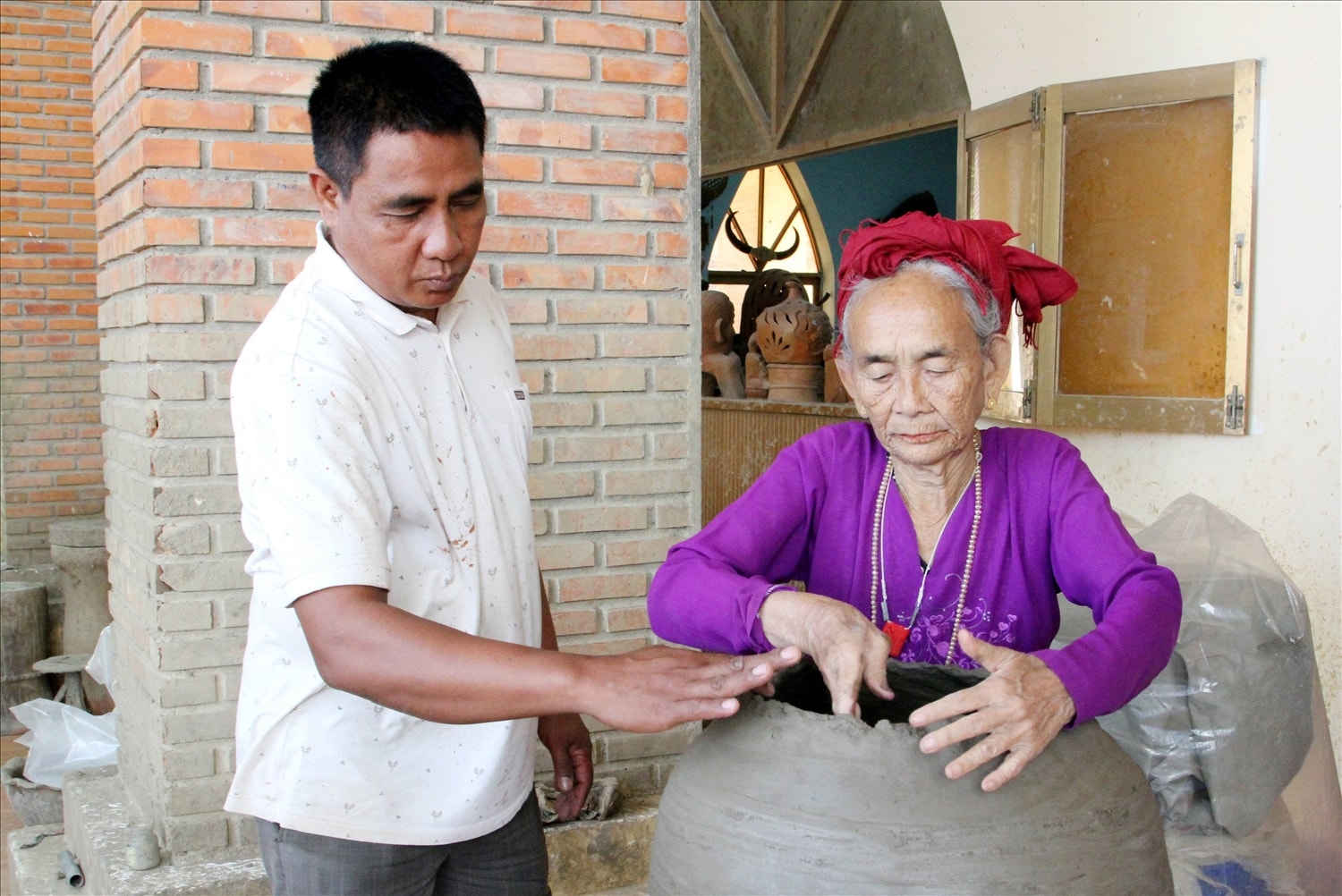 Ông Phú Hữu Minh Thuần, Giám đốc HTX Gốm Chăm Bàu Trúc trao đổi kỹ thuật chế tác bình gốm theo yêu cầu của khách hàng. 
