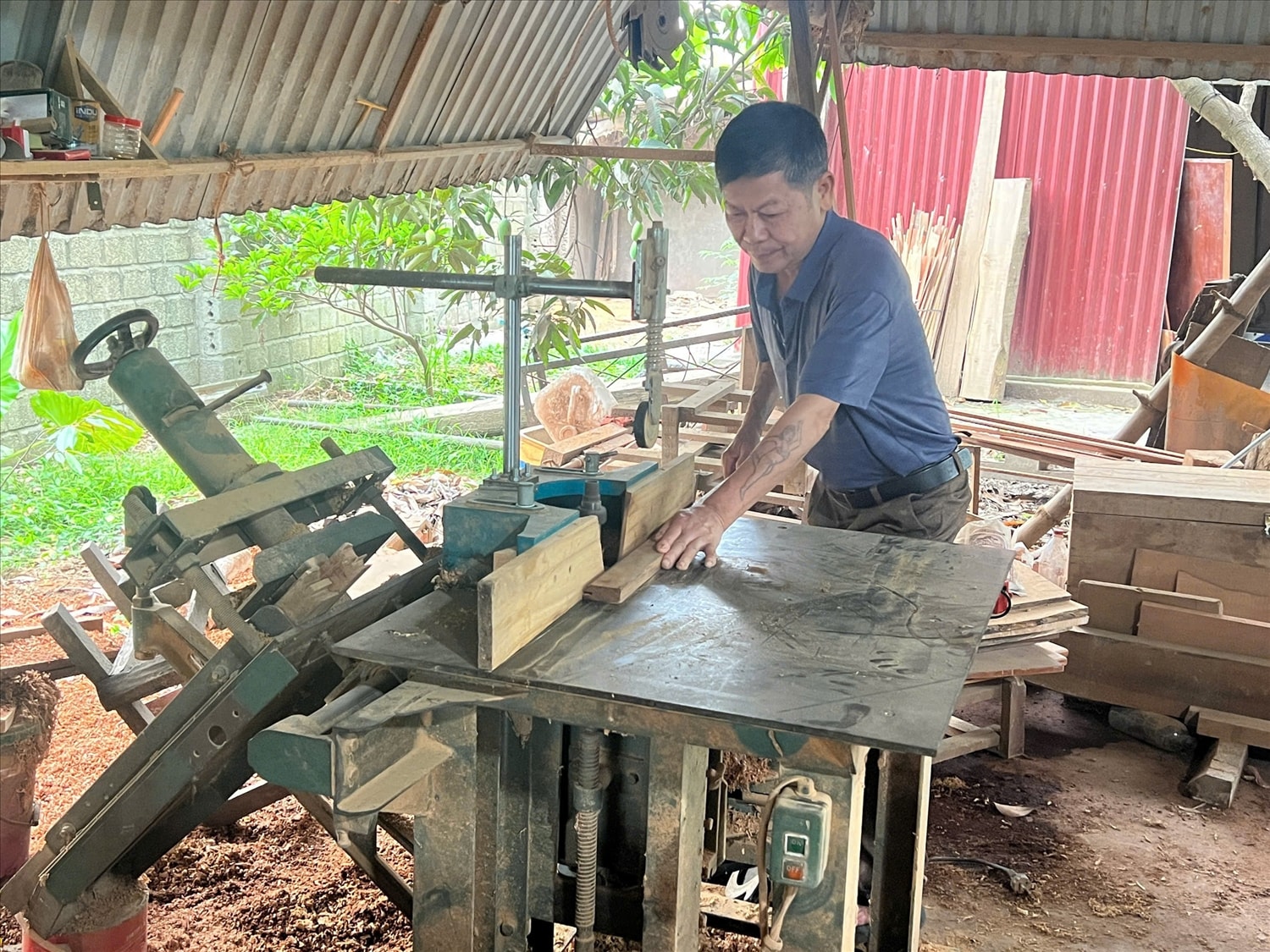 Anh Vũ Văn Hưng - chủ cơ sở chế biến đồ gỗ nội, ngoại thất ở thôn Đông Căm đang sản xuất đồ gỗ gia dụng.