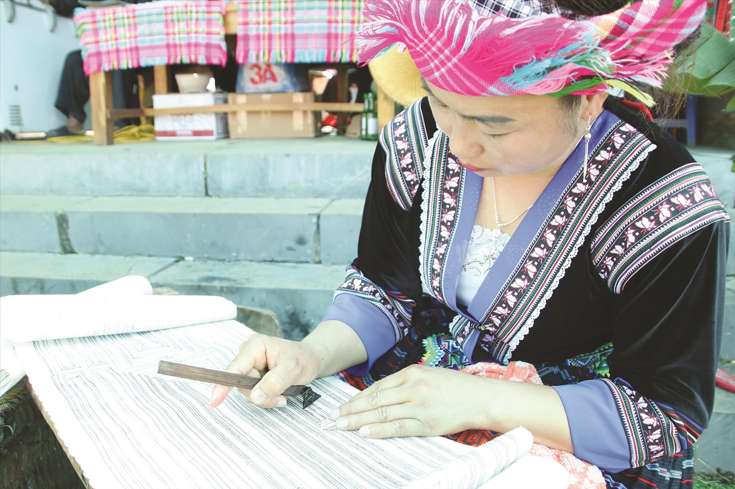 Khi vẽ hoa văn trên vải lanh, người phụ nữ Mông  đặt vải lên một tấm ván bằng phẳng và nhẵn