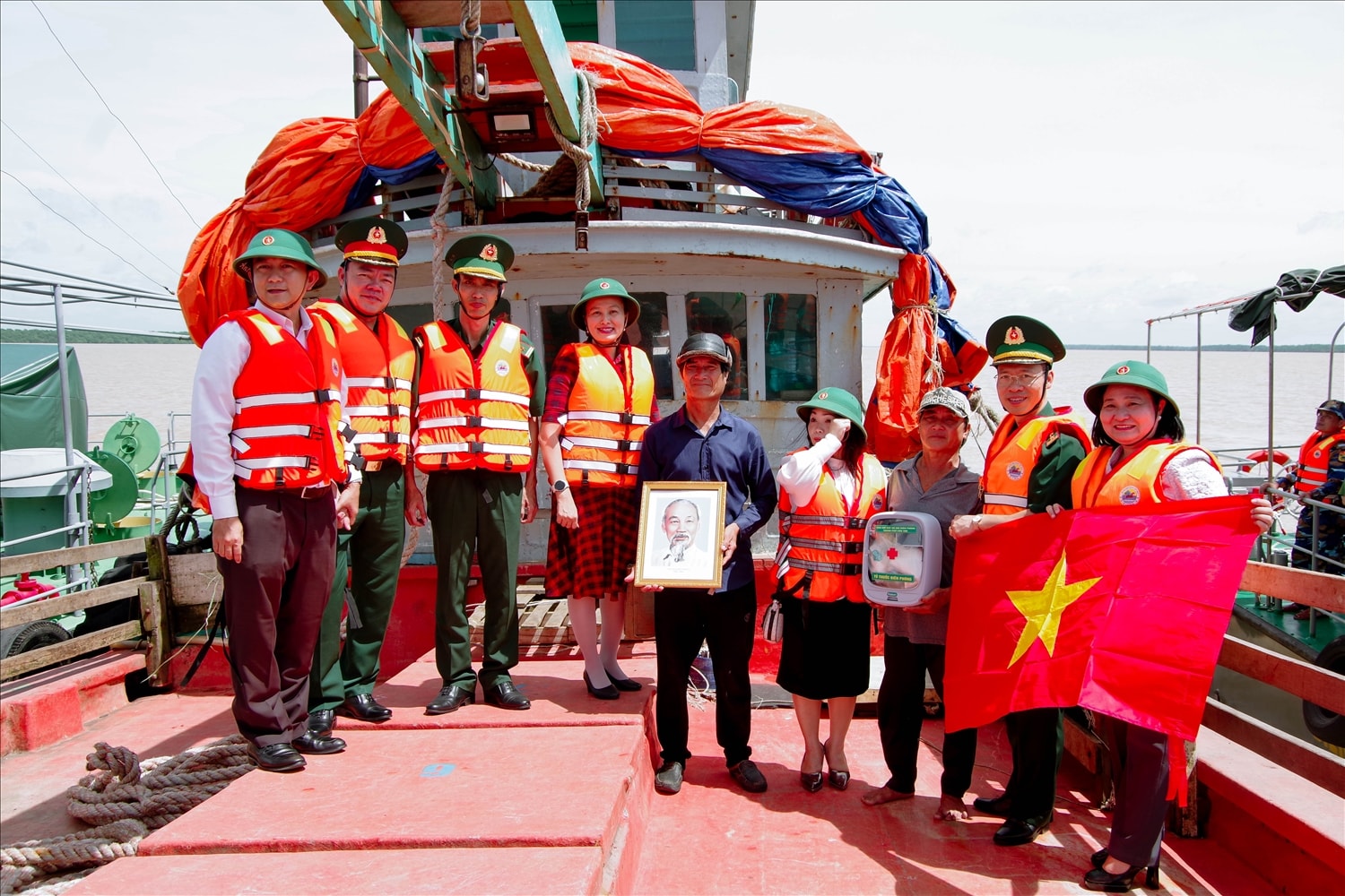 Tuần tra kiểm soát phát tờ rơi, tặng cờ tổ quốc ảnh Bác Hồ, tủ thuốc Biên phòng  và tuyên truyền chống khai thác IUU cho ngư dân. (Ảnh: Văn Long)