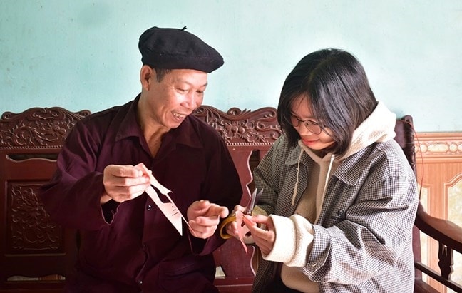 Người có uy tín Âu Đức Hợi, xã Đoan Hùng, tỉnh Phú Thọ truyền dạy cách cắt giấy dán trong lễ Chí Dịt cho thế hệ trẻ tại địa phương (Ảnh minh họa).
