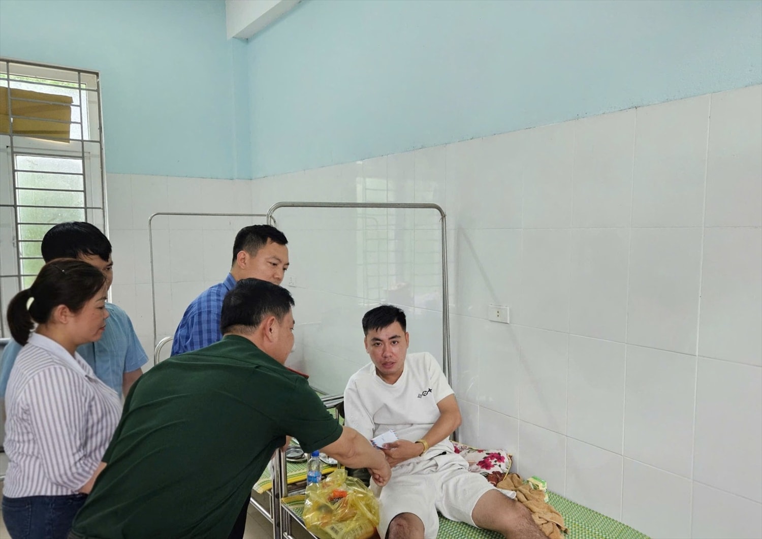 Nhân dân trên địa bàn xã Hiền Kiệt thăm hỏi, động viên Trung úy Lê Ngọc Vũ bị thương khi giúp dân phòng, chống bão số 5.(ảnh Thái Thanh)
