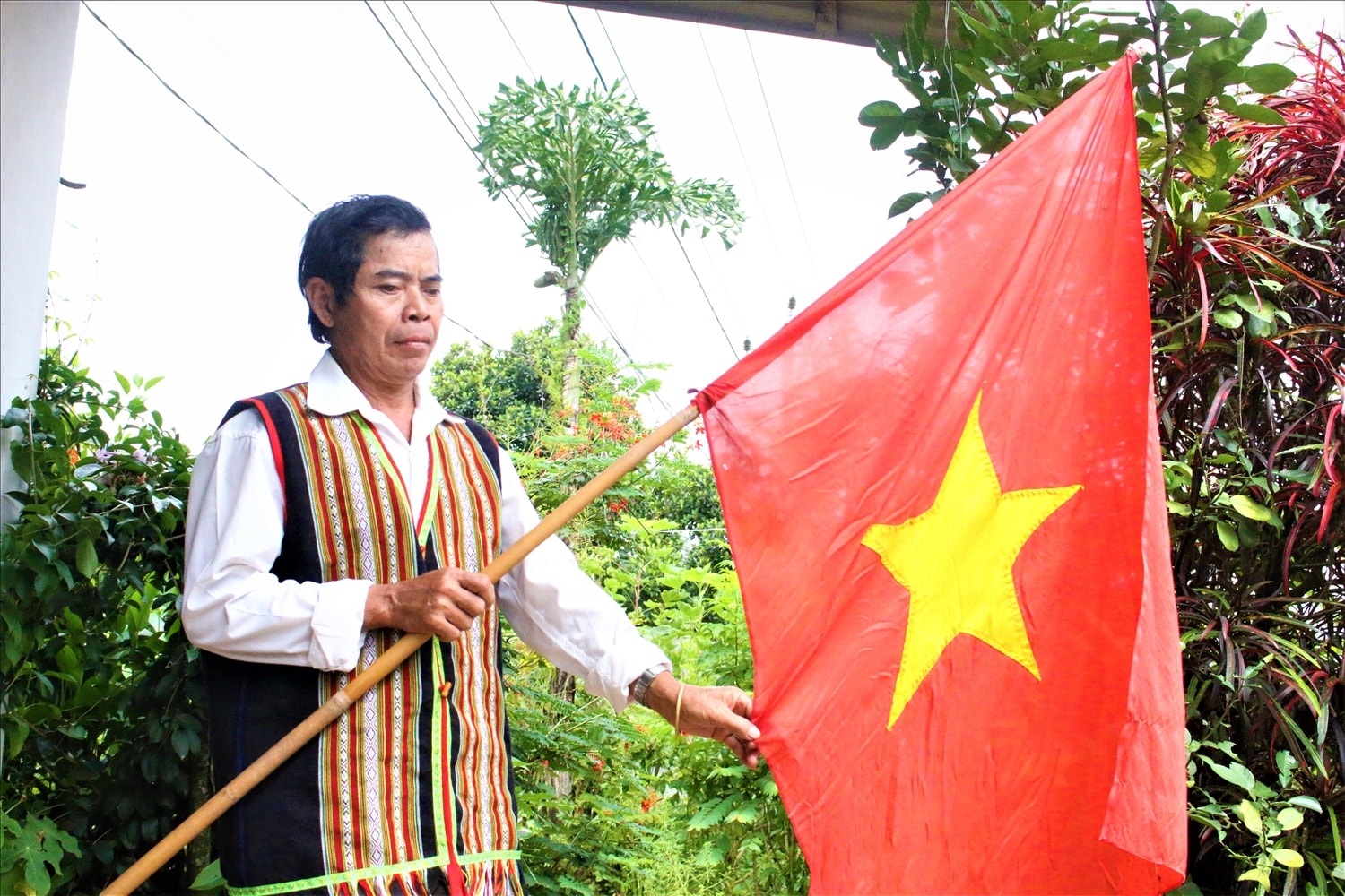Ông A Nhum, làng Kon Kơ Tu, xã Đăk Rơ Wa chuẩn bị lá cờ Tổ quốc để treo chào mừng kỷ niệm 80 năm Cách mạng Tháng Tám và Quốc khánh 2/9. (Ảnh: Ngọc Chí)
