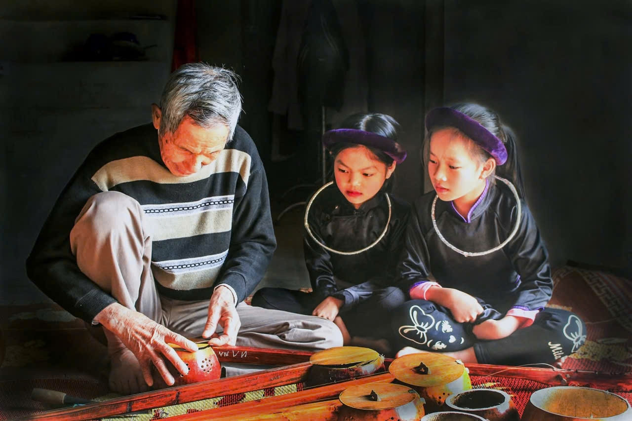 Nghệ nhân Ưu tú Lương Thiêm Phú đang truyền dạy, hướng dẫn trẻ em chế tác đàn tính (Ảnh:  Mỹ Dung)