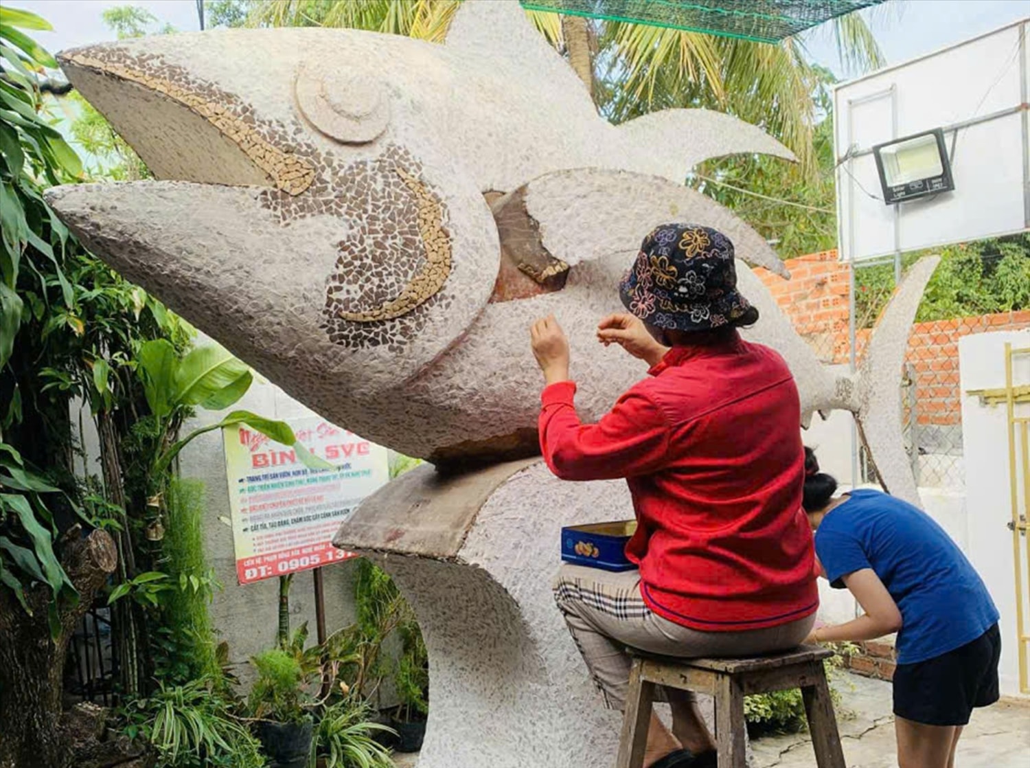 Các nghệ nhân tỉ mỉ lắp từng mảnh nhỏ vỏ gáo dừa lên thân cá (ảnh: H.T)