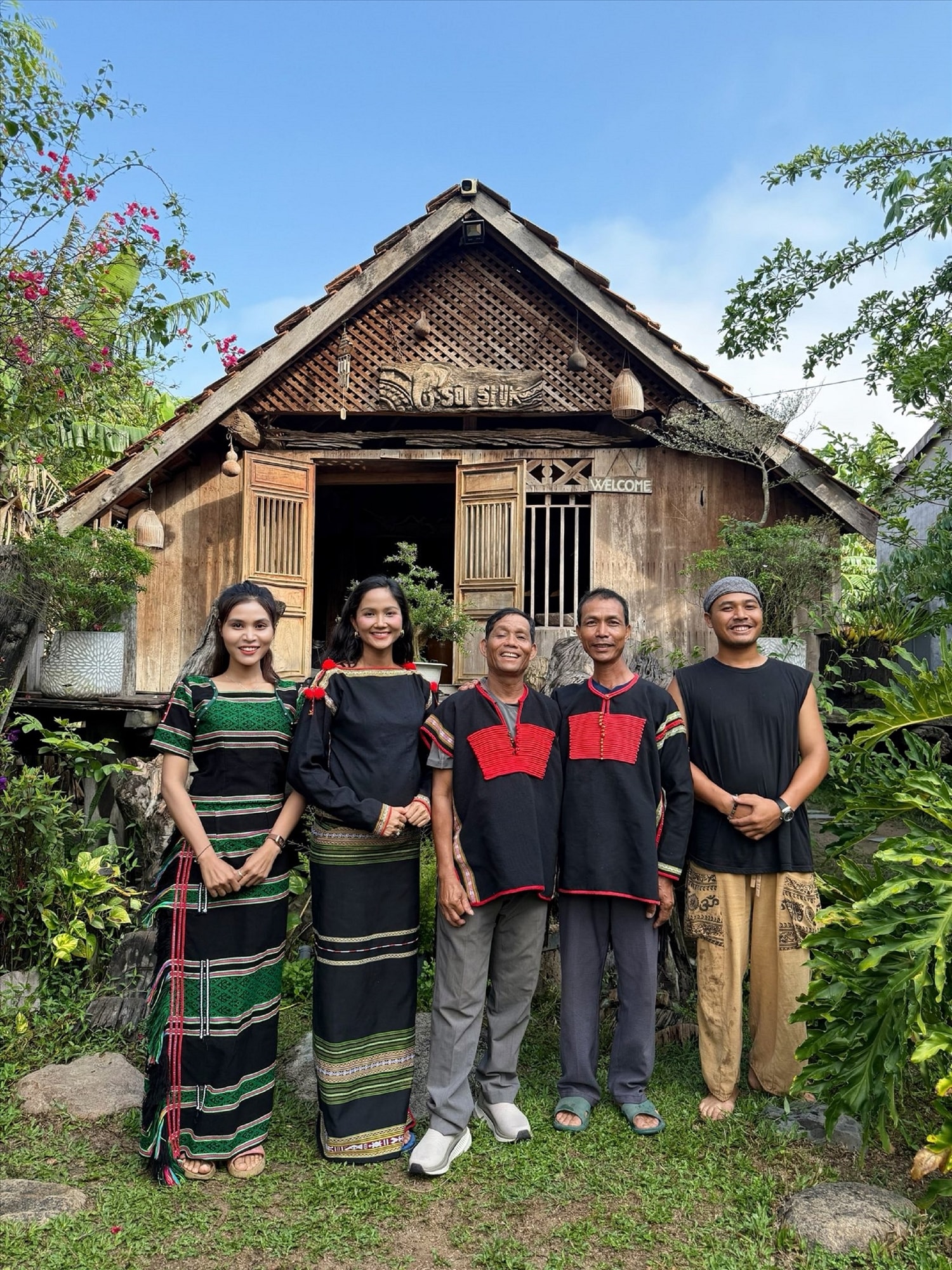 H’huyn Sruk (trái) cùng em trai Y Sôl (phải) và Hoa hậu H’hen Niê cùng các nghệ nhân M’nông trước Y Sôl House homestay 