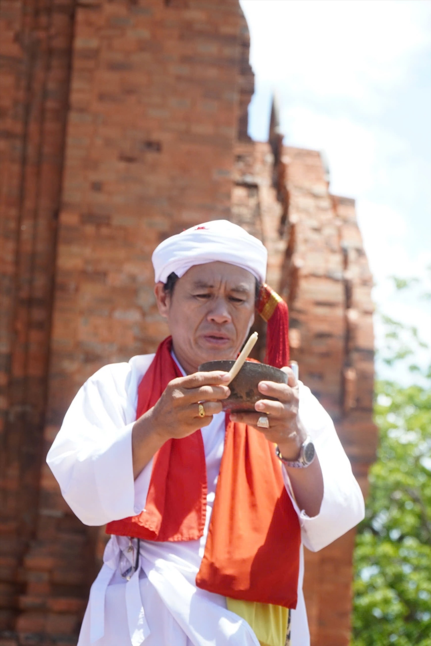 Vị chức sắc người Chăm dùng chén Patil bằng đồng dùng xác định vị trí đào giếng. Ảnh: Wa Praong.