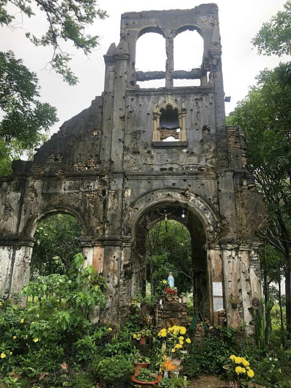 Cận cảnh nhà thờ H'Bâu, phía trên là tháp chuông, phía dưới là cổng chính vào nhà thờ cổ H'Bâu, trên tường chi chít vết đạn do chiến tranh - ảnh Xuân Hiền.