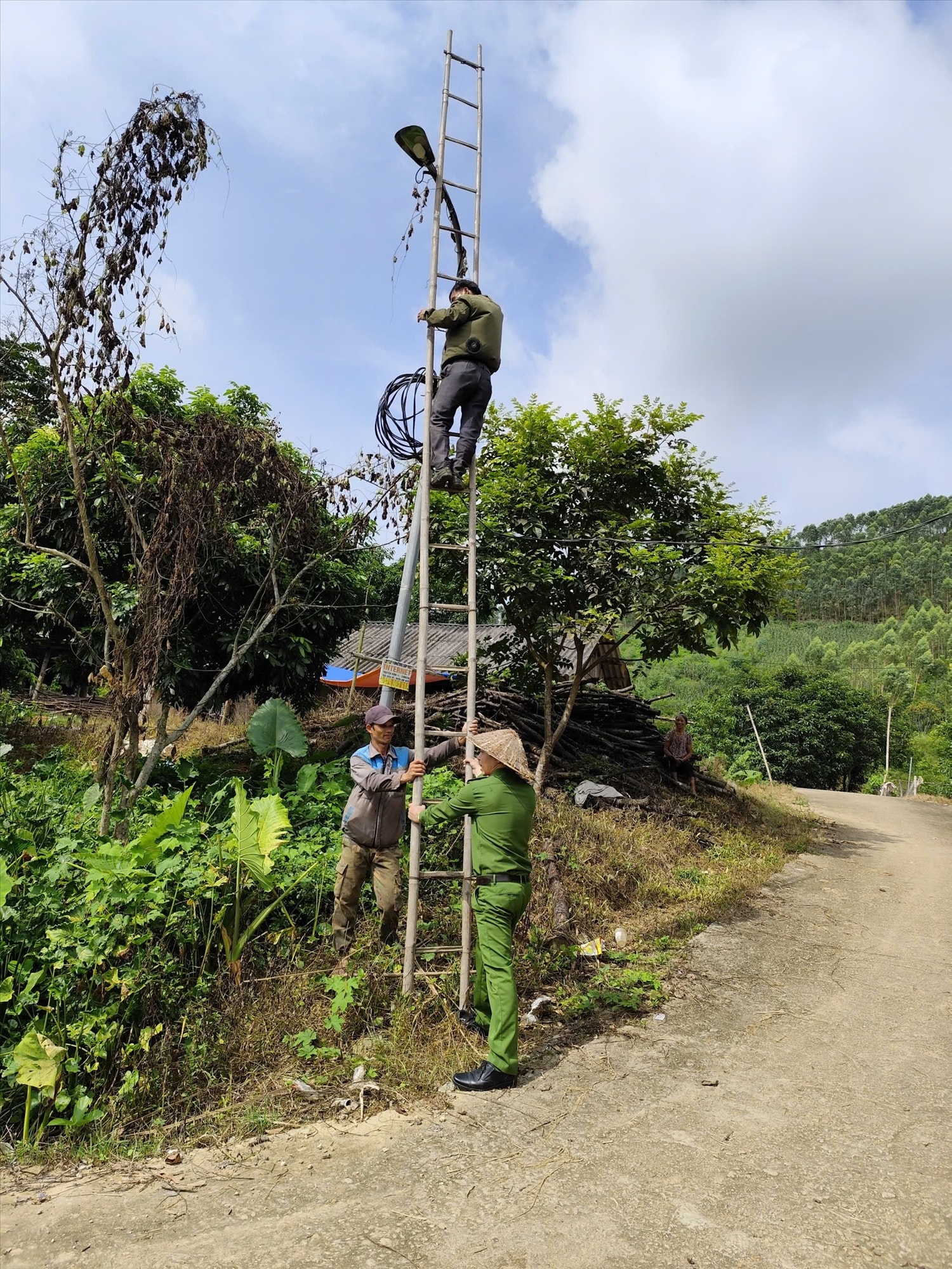 Trưởng thôn Vũ Văn Linh (người trèo trên thang) và Công an xã cùng người dân trực tiếp lắp đặt đèn đường chiếu sáng trên địa bàn thôn Cả 