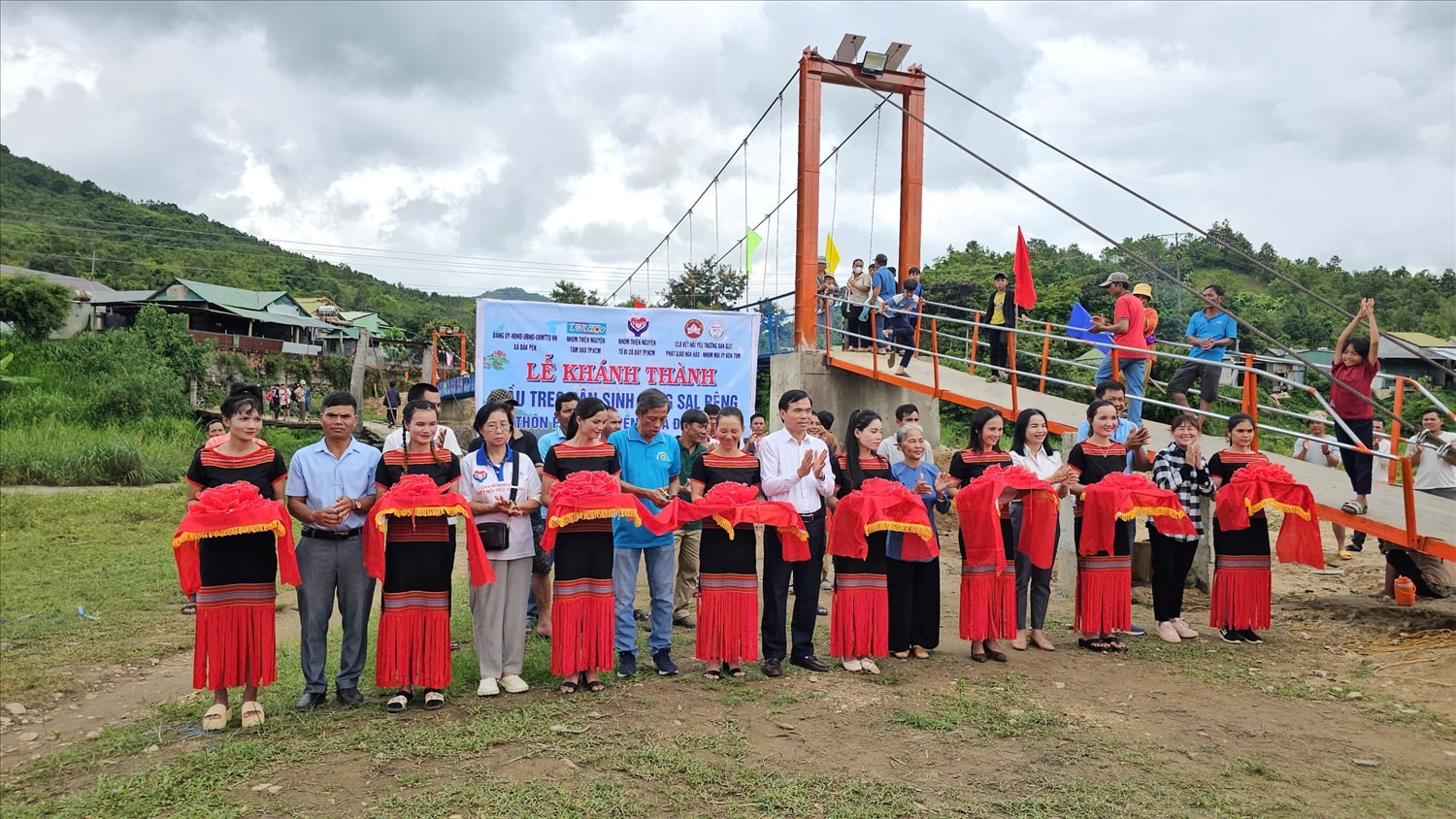 Lãnh đạo xã Đăk Pék và đại diện các nhóm thiện nguyện cắt băng khánh thành cầu treo dân sinh bắt qua suối Đăk Mỹ. (Ảnh: Ngọc Chí)