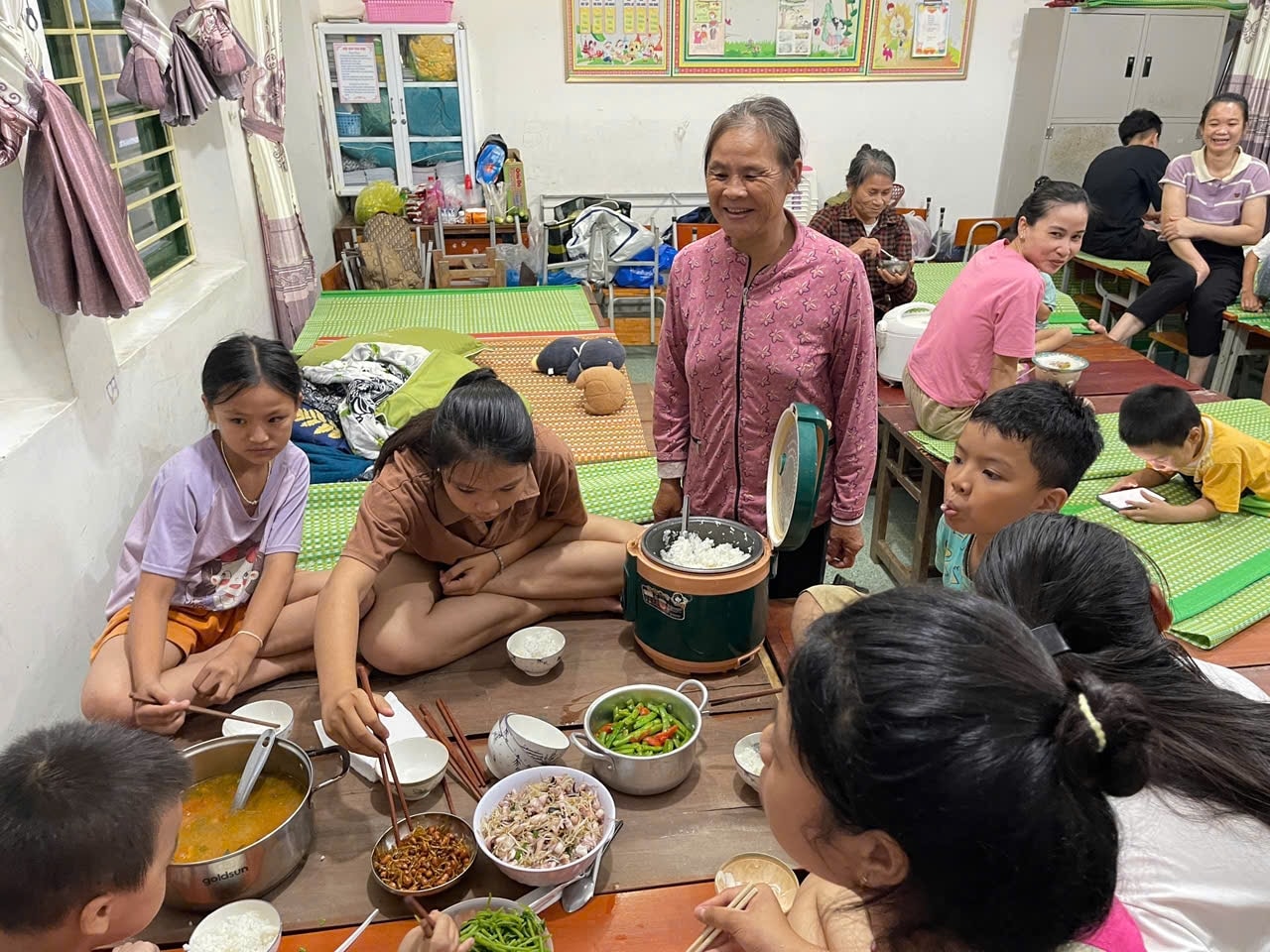 Bà Thái Thị Thảo (57 tuổi) ở xóm Bắc Chiến Thắng nói: Tôi sợ mấy cháu ăn uống kham khổ sẽ đổ bệnh, nên đưa bếp ga lên nấu thức ăn để đảm bảo hơn. Thấy các cháu ăn uống ngon lành, mình cũng vui hơn - Ảnh: Thanh Hải