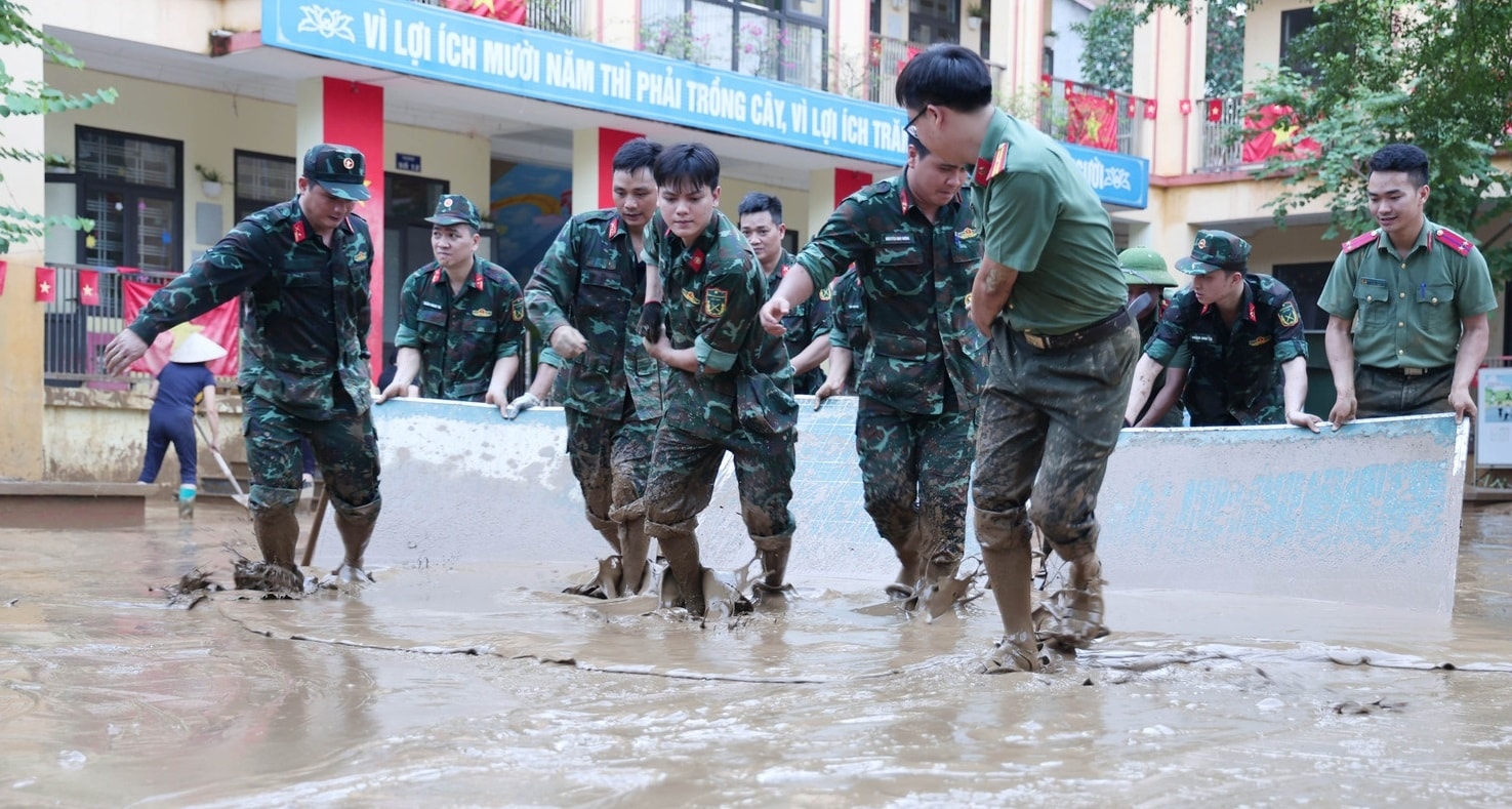 Các lực lượng công an, quân đội tham gia hỗ trợ các trường dọn bùn đất sau mưa lũ (ảnh Trọng Bảo)