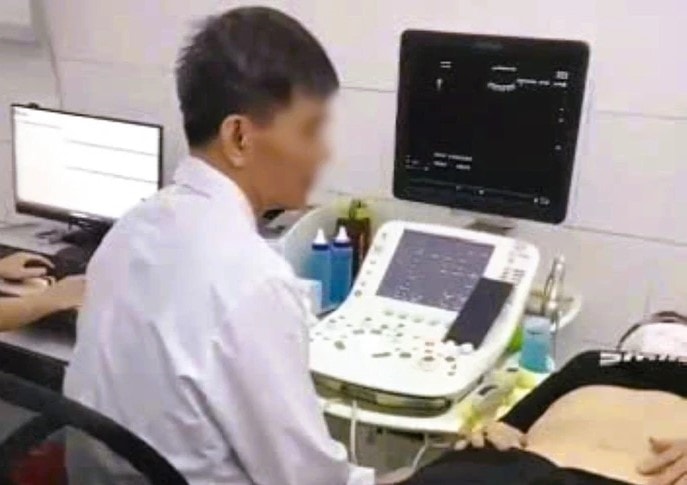 Hình ảnh bác sĩ vừa siêu âm vừa xem bóng đá trên điện thoại gây bức xúc. Ảnh cắt từ clip