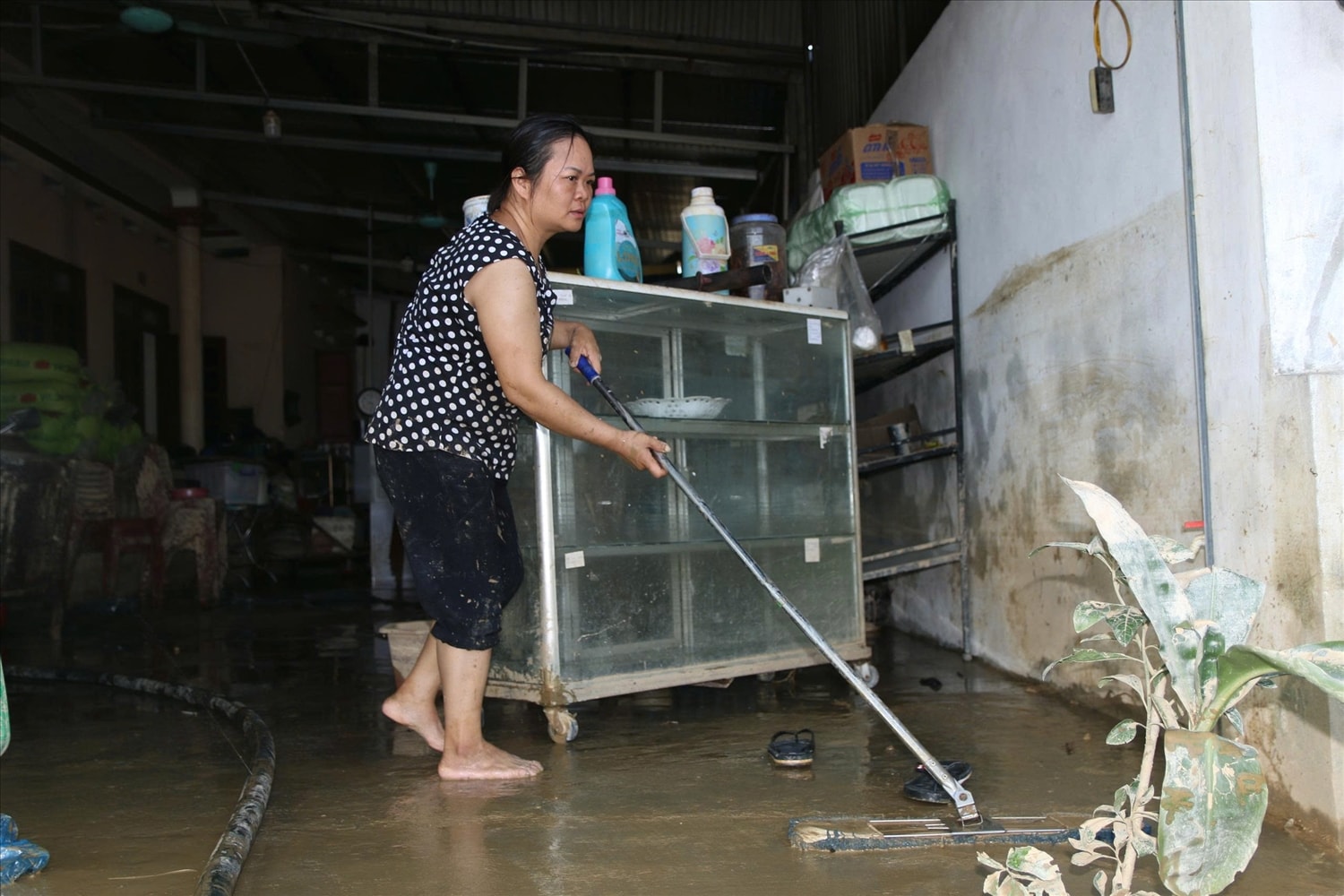 Bà Vũ Bảo Ngọc, tổ dân phố Cậy, phường Linh Sơn, đang dọn dẹp, ủn bùn ra khỏi nhà sau nước lũ rút. (Ảnh: Thế Toàn)
