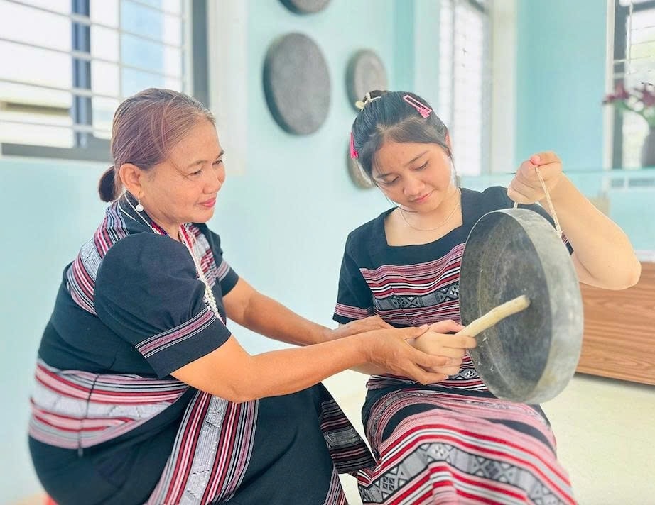 Bà Đinh Thị Tuyết (trái) hướng dẫn em Đinh Thị Kim Ngân cách đánh chinh tía (chiêng 5). (Ảnh: D.Đ)