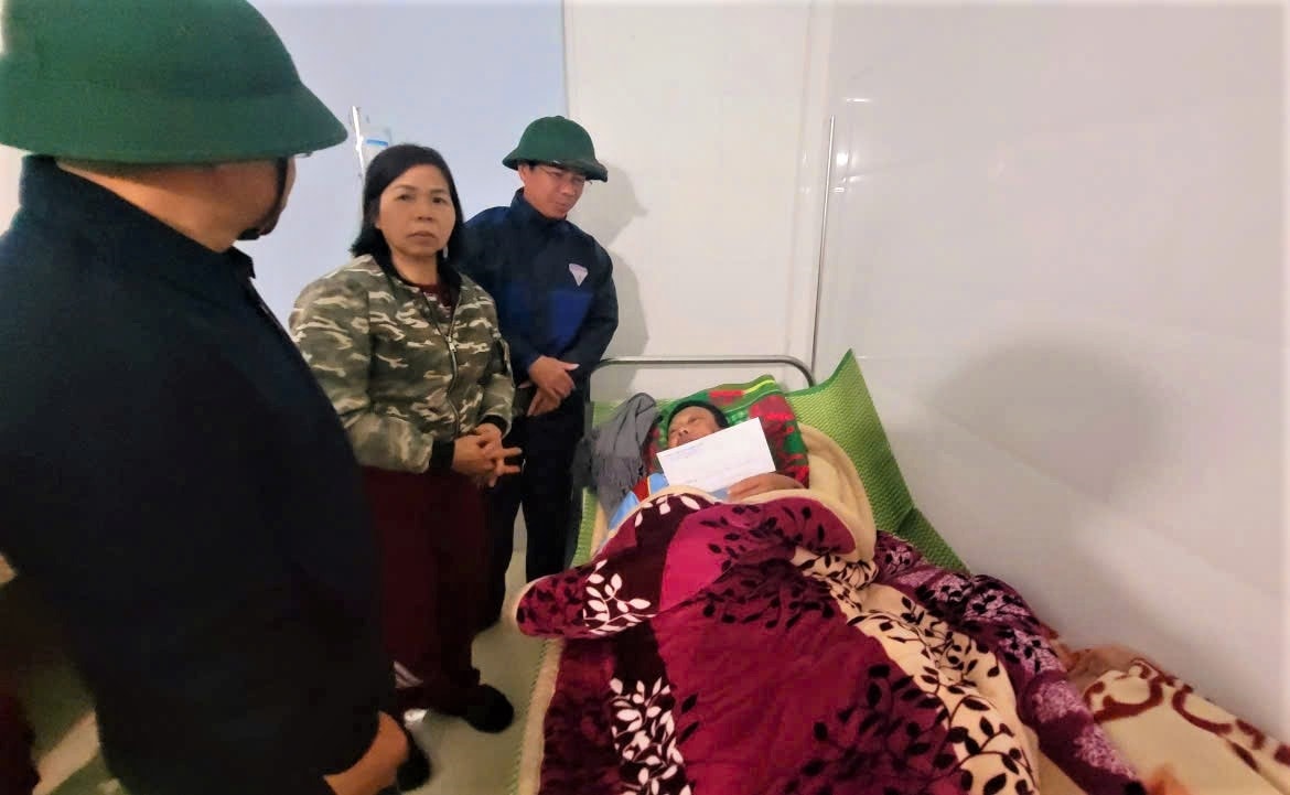 Lãnh đạo xã Ngọc Linh đến thăm hỏi, động viên ông Phạm Quốc Tuấn bị thương do sạt lở đất và đang điều trị tại Trạm Y tế xã. (Ảnh: Ngọc Chí)