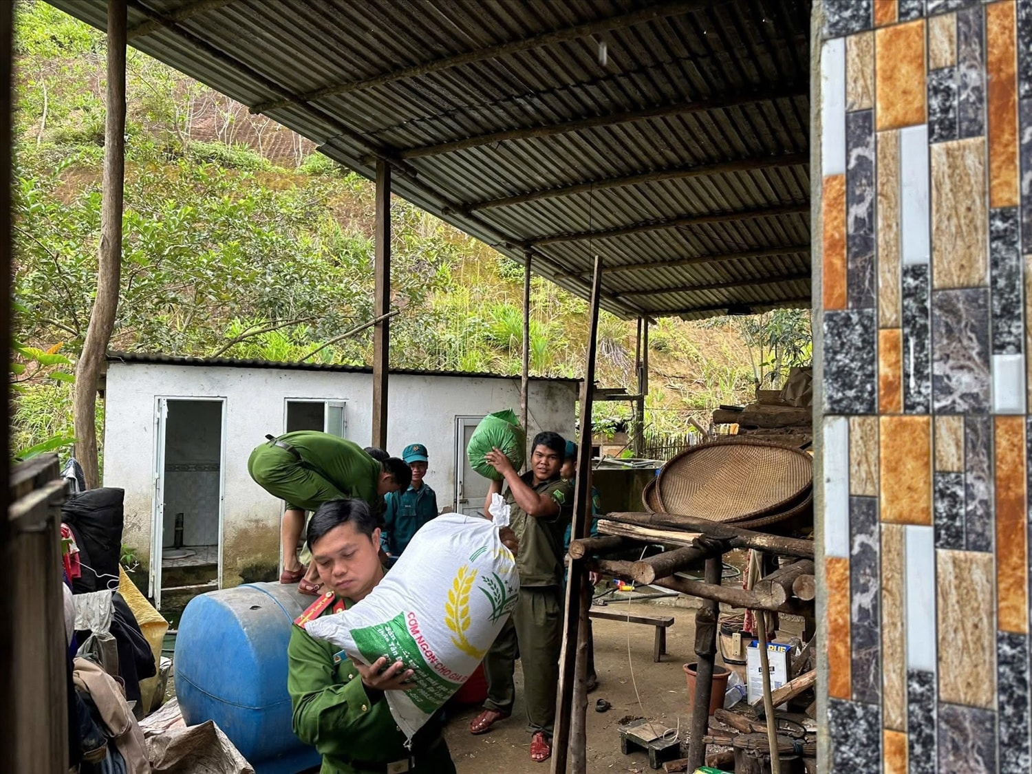 Lực lượng chức năng xã A Vương hỗ trợ di dời đồ đạt cho người dân sau khi phát hiện vết nứt trên đồi. (Ảnh Thi Thi)