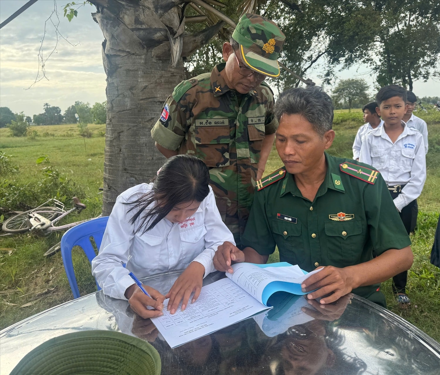 Trung uý, Chin Nak ( người đứng) Đại đội 3, Tiểu đoàn 335 chứng kiến các em ký nhận học bổng do cán bộ ĐBP Phú Mỹ trao tặng 