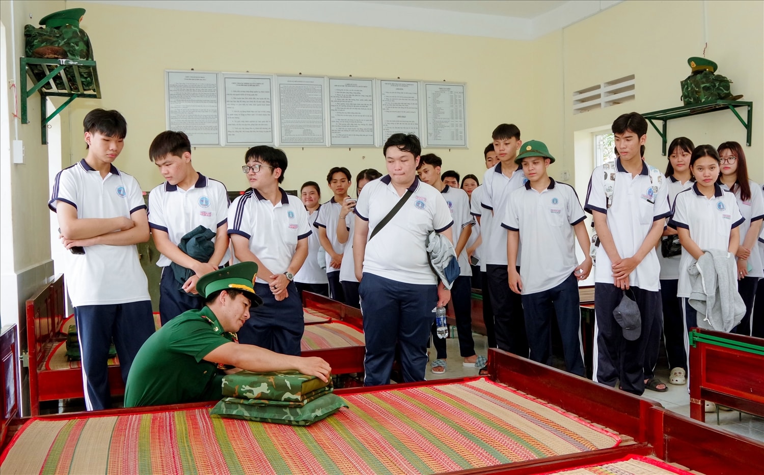 Các em học sinh trải nghiệm cách sắp xếp ngăn nắp chăn màn từ cán bộ đồn Biên phòng Vĩnh Hải 