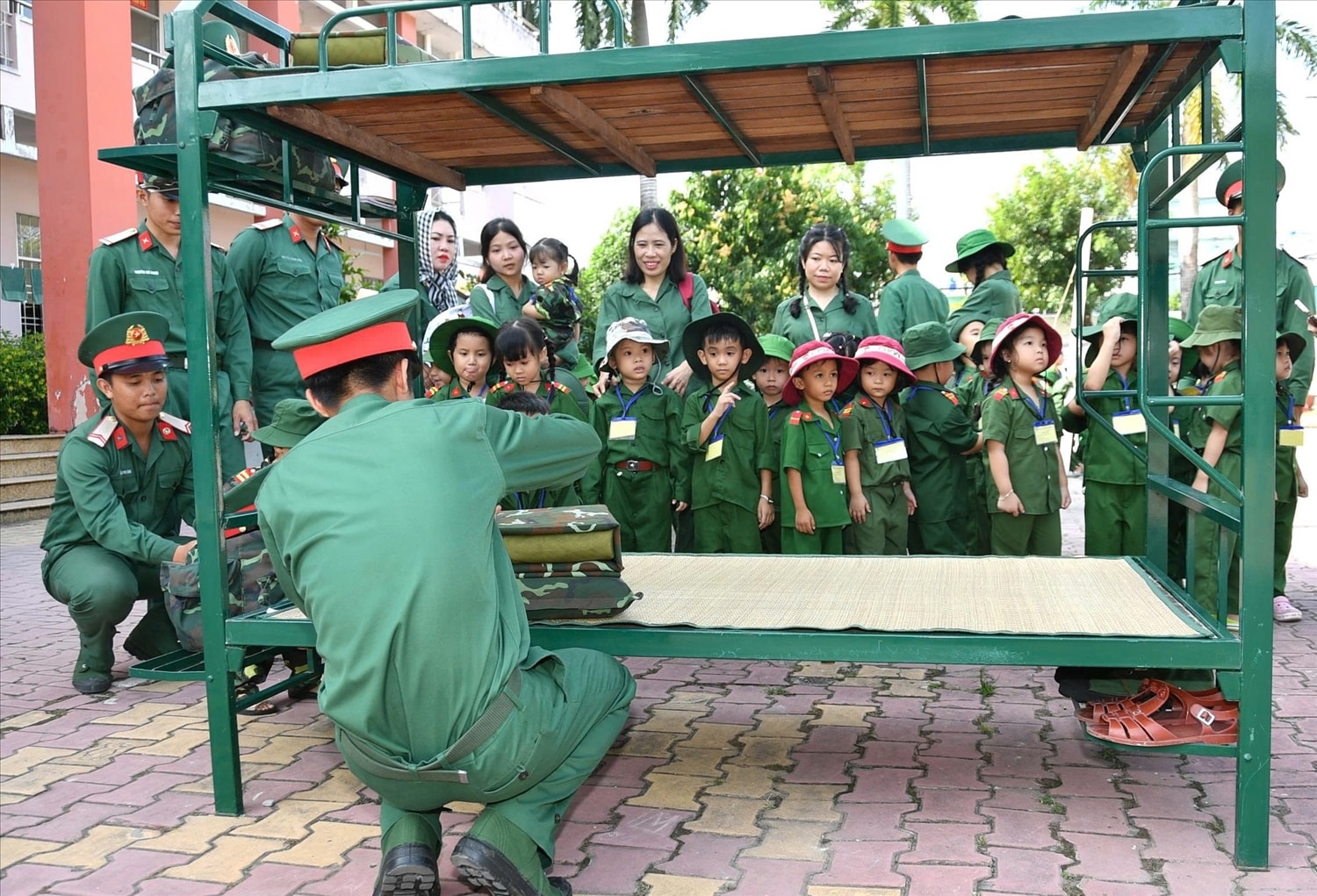 Các chú bộ đội hướng dẫn các cháu thiếu nhi học cách xếp chăn màn. Ảnh: Phương Vũ 