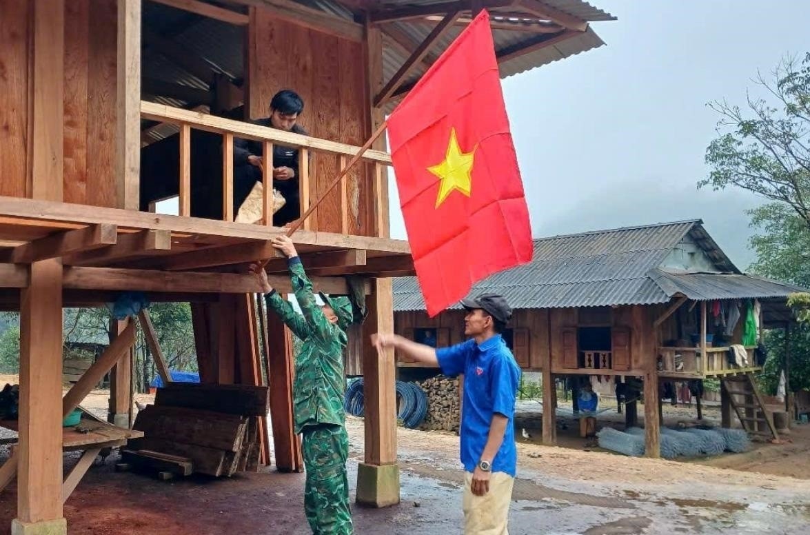 Cán bộ Bộ đội Biên phòng tỉnh Quảng Trị và đồng bào Vân Kiều ở xã Tà Rụt treo cờ Tổ quốc chào mừng Đại hội đại biểu toàn quốc lần thứ XIV của Đảng (Ảnh: Tiêu Dao)