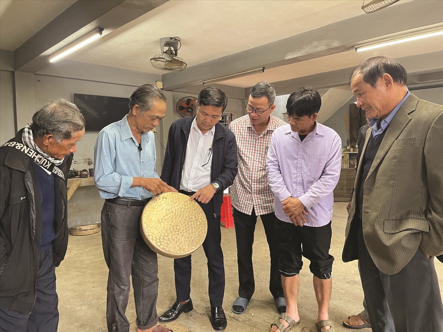 Nghệ nhân Ưu tú Dương Ngọc Tiển (người thứ hai bên trái) giới thiệu chiếc chiêng mới đúc