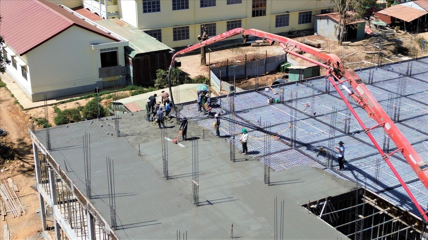 Các công nhân đang làm việc xuyên trưa, đổ bê tông sàn tầng 3 khu ký túc xá,  Trường phổ thông nội trú liên cấp TH – THCS xã Rờ Kơi. (Ảnh: Ngọc Chí)