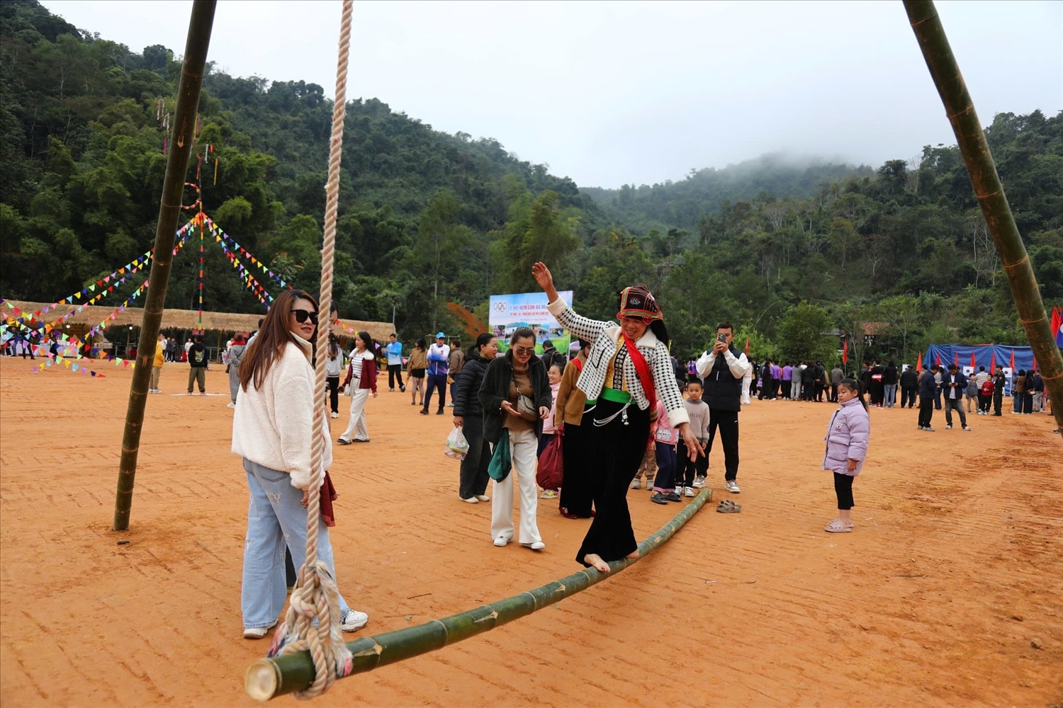 Trong không gian rộn ràng ngày Tết, người Thái trong trang phục truyền thống rực rỡ tay trong tay vui hội giữa sân bản