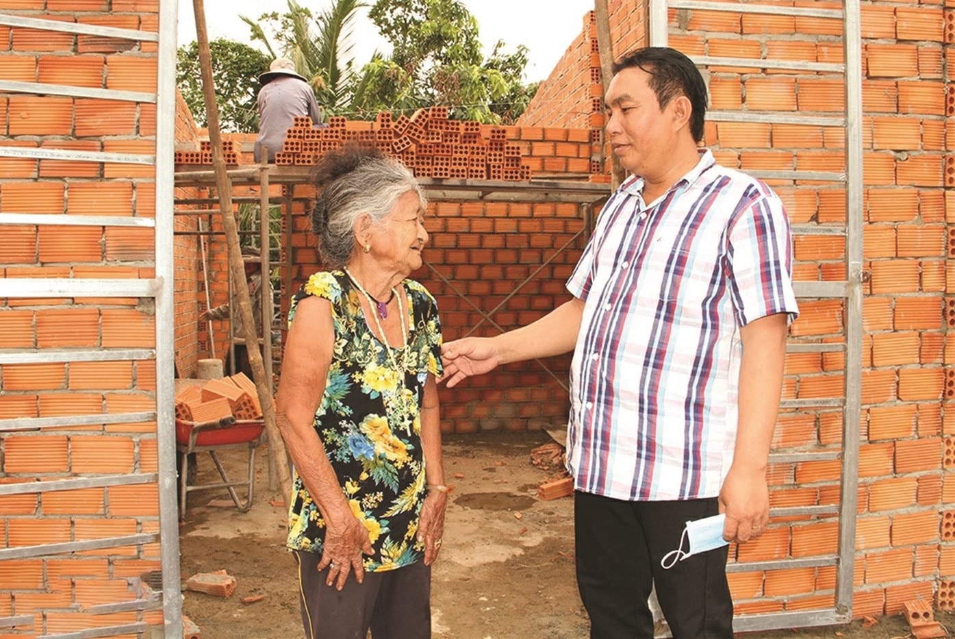 Ông K’Luận, Trưởng ban Công tác Mặt trận ấp 4, xã Tà Lài, tỉnh Đồng Nai thăm hỏi bà Ka Tờ trong quá trình hoàn thiện căn nhà kiên cố do Nhà nước hỗ trợ kinh phí xây dựng. Ảnh: Văn Truyên