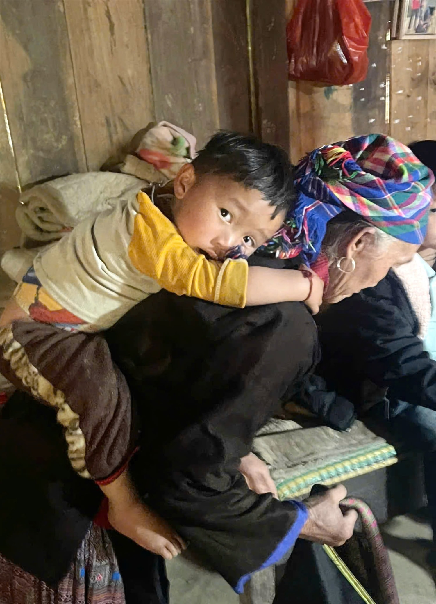 Gương mặt ngây thơ nhưng đượm buồn của bé Giàng A Tông trên lưng bà nội.  Bé vẫn chưa cảm nhận hết nỗi đau vắng bóng cả cha lẫn mẹ