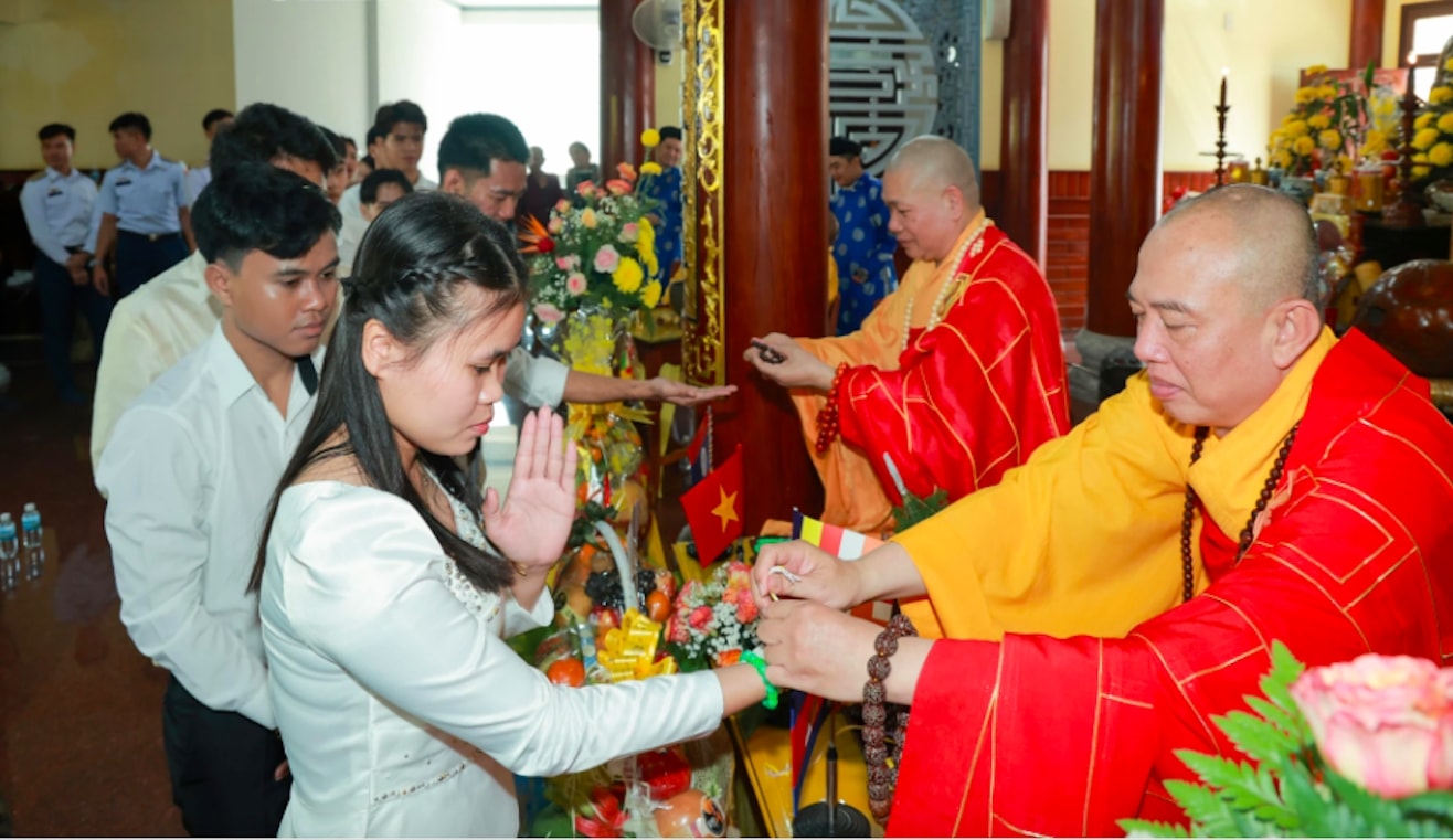 Nghi thức buộc chỉ cổ tay cầu may dành cho các sinh viên, học viên Lào và Campuchia. (Ảnh: N.T)