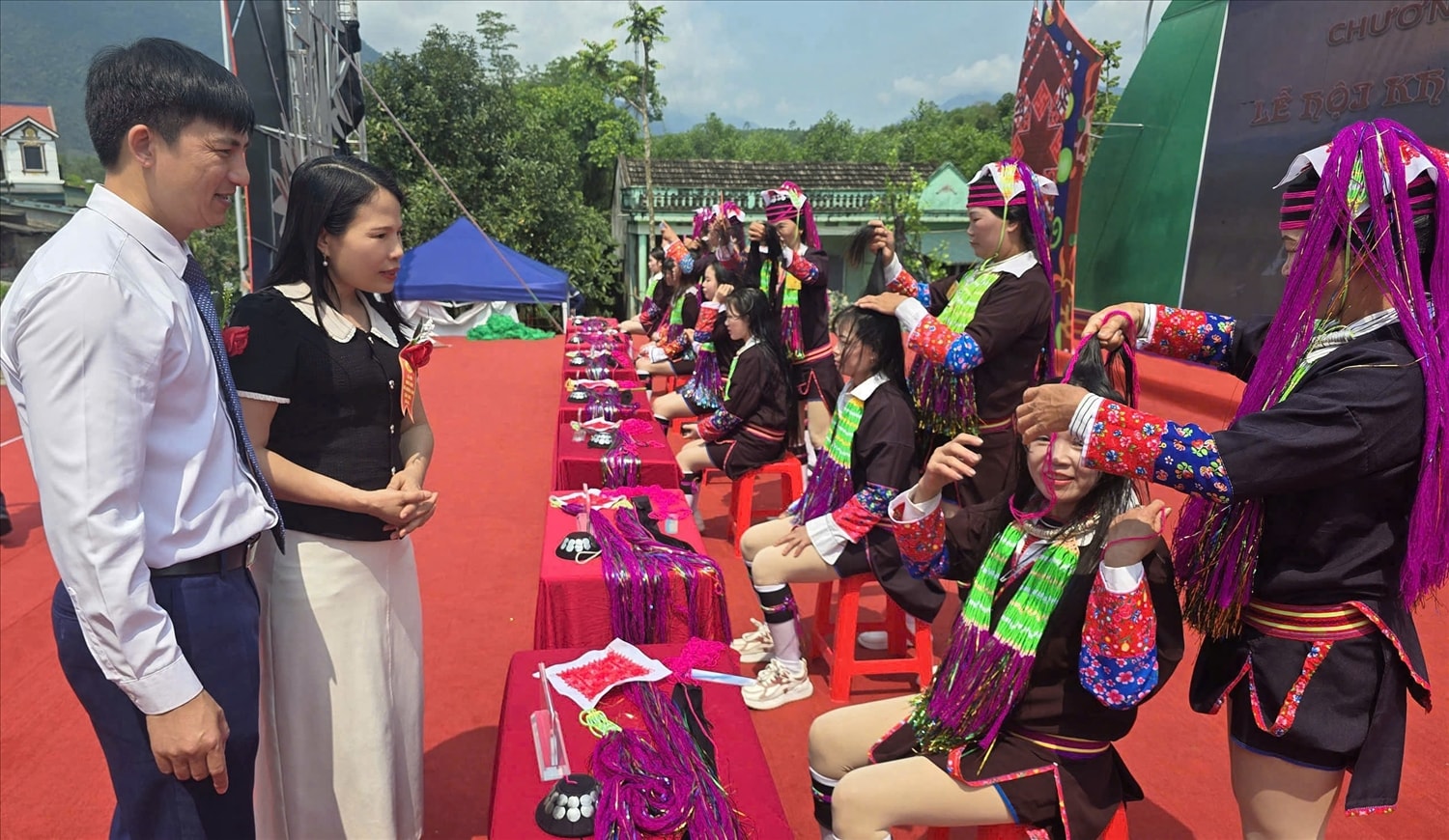 Phó Giám đốc Sở Dân tộc và Tôn giáo tỉnh Quảng Ninh Ân Thị Thìn cùng lãnh đạo xã Đường Hoa theo dõi phần thi vấn tóc – nét văn hóa đặc sắc của đồng bào vùng cao đang được bảo tồn và phát huy gắn với phát triển du lịch cộng đồng. Ảnh: Mỹ Dung