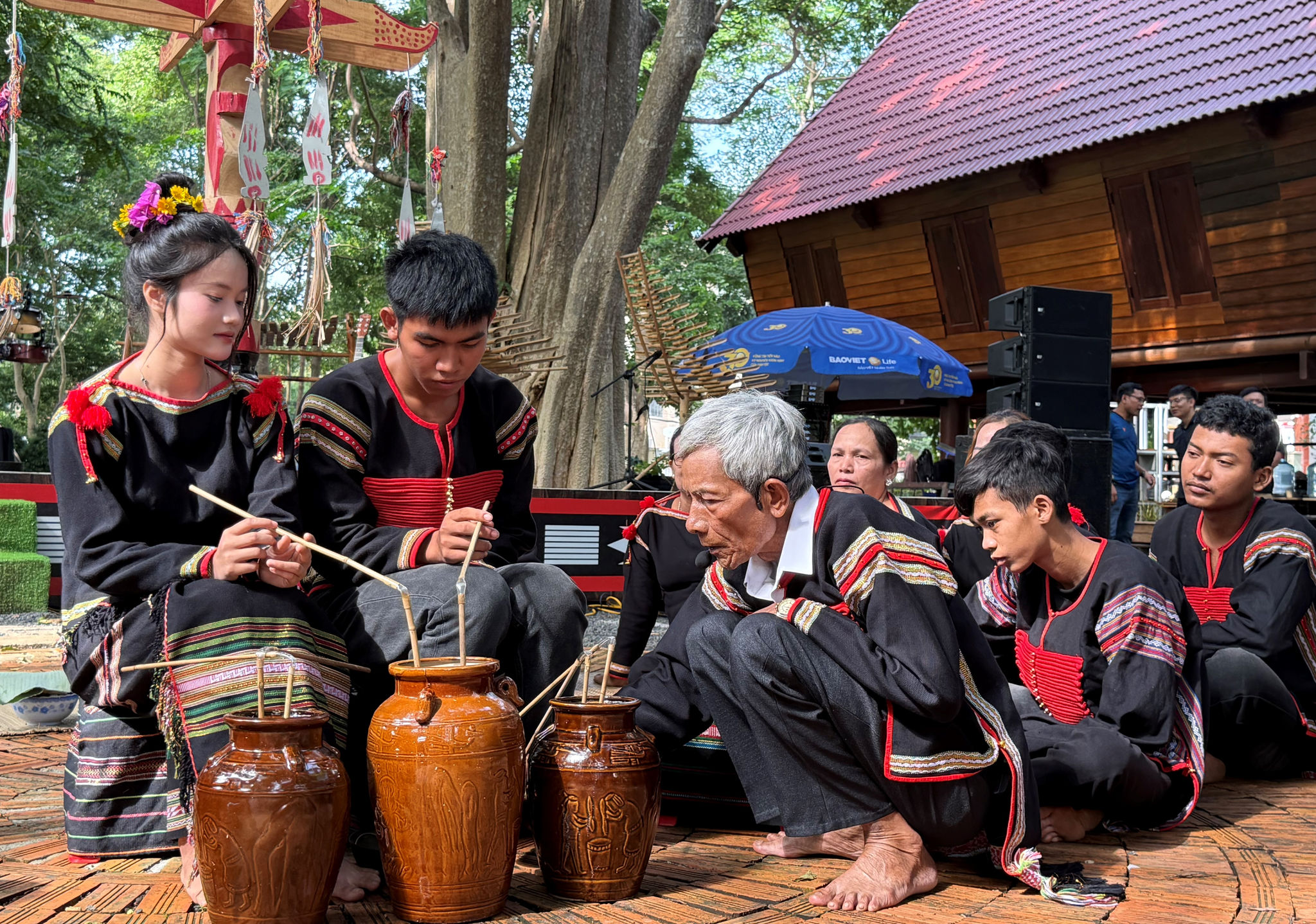 Già làng dùng bông gòn nhúng vào tô đồng đựng nước rồi quét lên chân đôi vợ chồng ba lần.