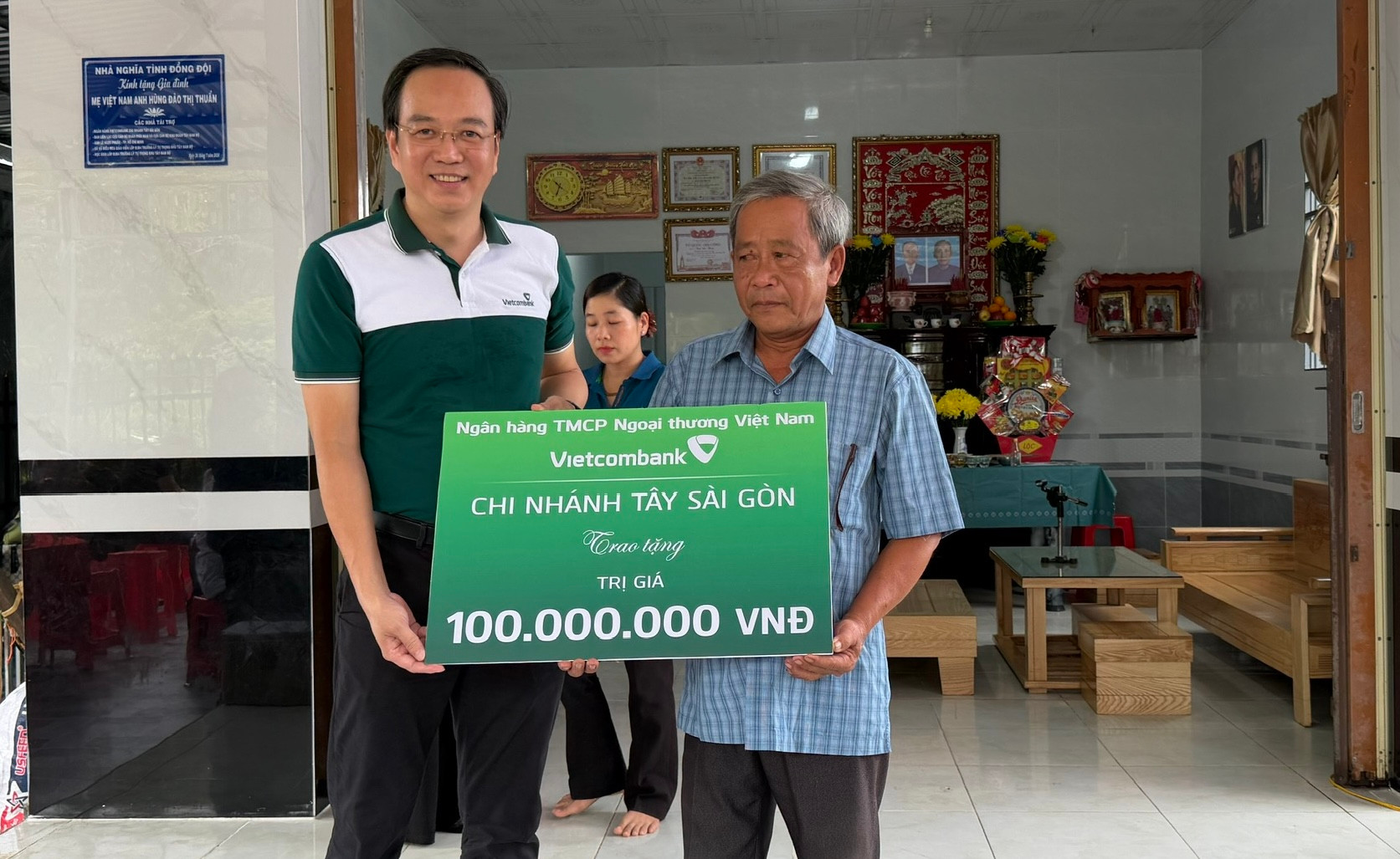 Ông Nguyễn Chí Cường, Giám đốc Vietcombank Chi nhánh Tây Sài Gòn trao kinh phí cho ông Trần Việt Trường là con út của Mẹ Việt Nam Anh hùng Đào Thị Thuẩn