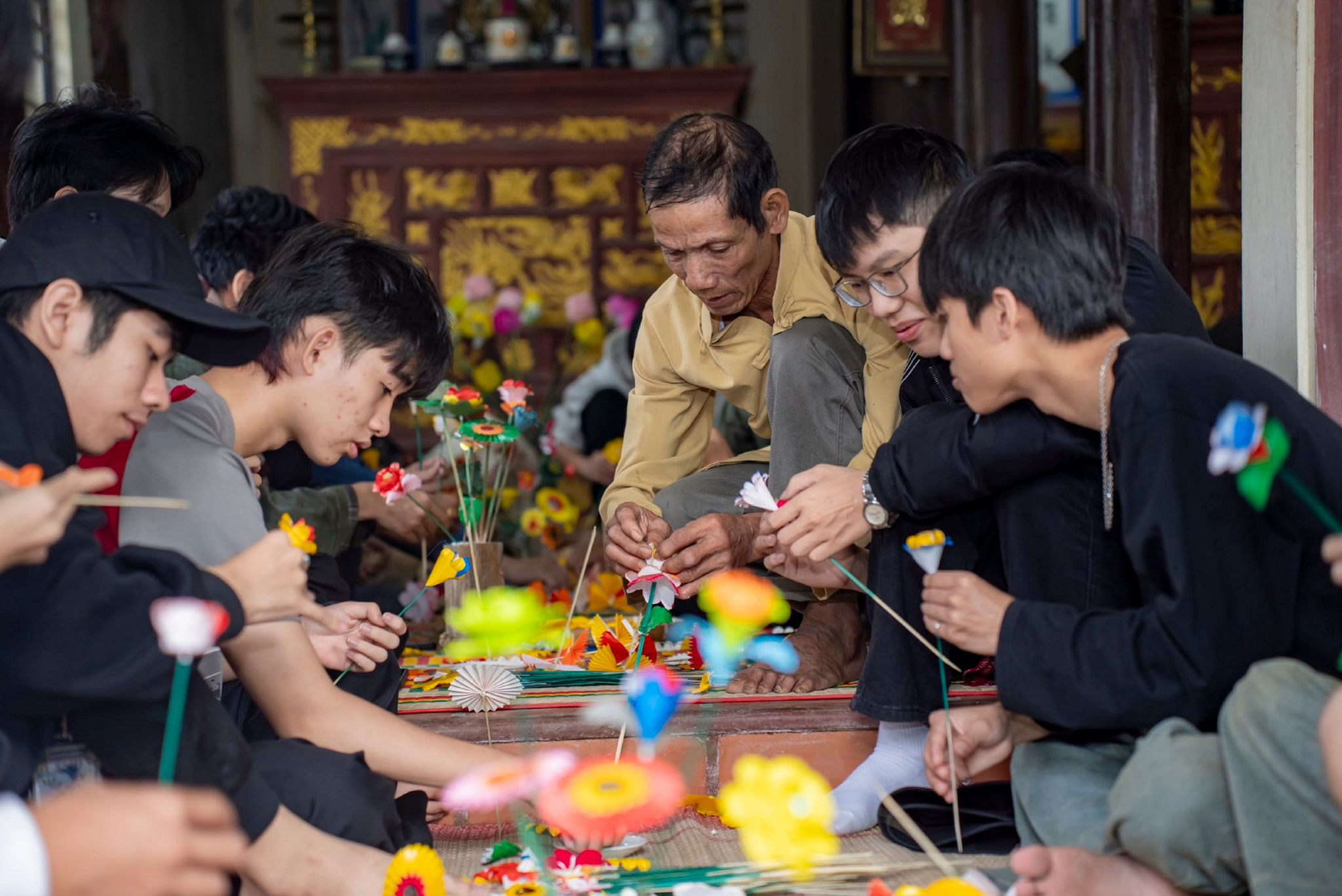 Nghệ nhân Trần Phú vừa làm hoa, vừa hướng dẫn người trẻ và du khách trải nghiệm nghề truyền thống.