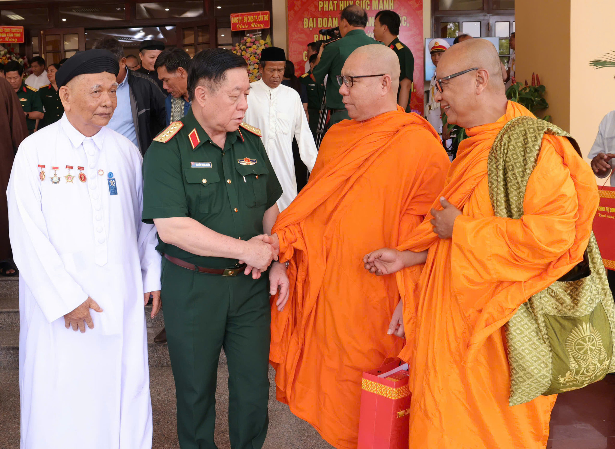 Đại tướng Nguyễn Trọng Nghĩa, ân cần thăm hỏi động viên các vị chức sắc tham dự chương trình gặp mặt già làng, trưởng thôn, trưởng ấp, trưởng khu, Người có uy tín, chức sắc tôn giáo khu vực Nam Bộ năm 2026. Trong ảnh: Đại tướng nắm tay, trò chuyện cùng Thượng toạ Lý Đức. Ảnh: Như Tâm