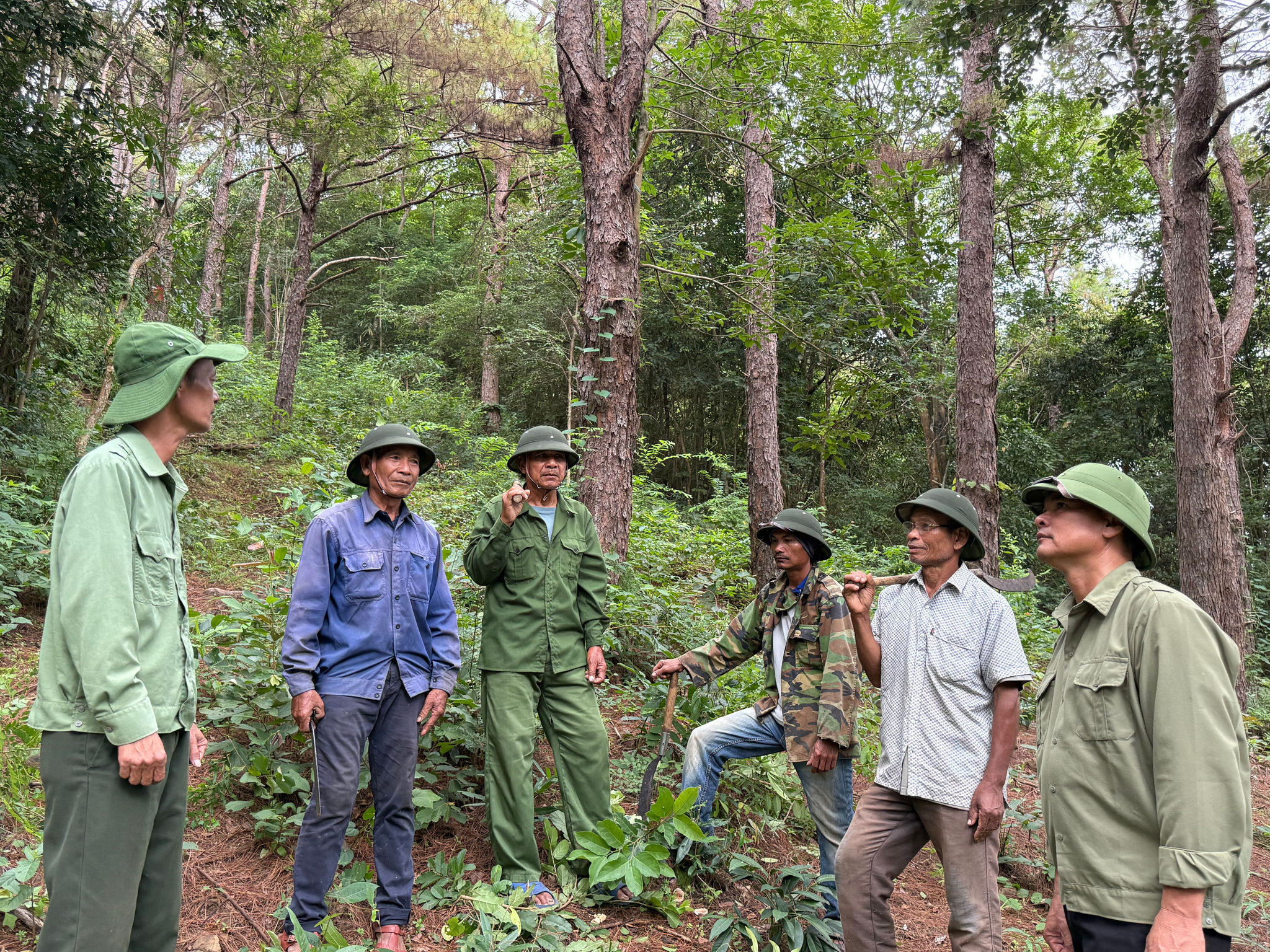 Ông Y Bliêng (thứ 2 bên trái) trao đổi thông tin với người dân trong tổ nhận khoán